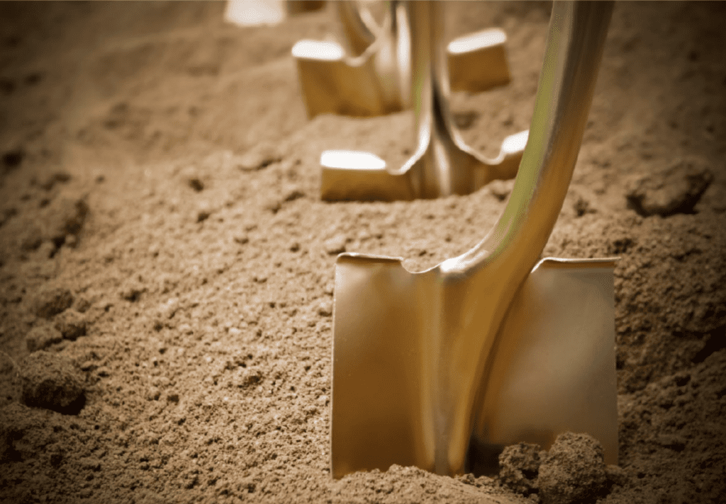 Golden colored shovels lined up in dirt for ceremonial groundbreaking